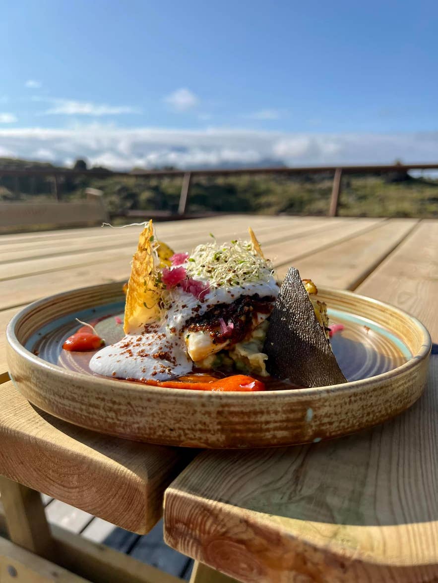 A beautifully plated dish with vibrant colors, including bright sauces and garnishes, on a rustic brown plate. A beautifully plated dish with vibrant colors, including bright sauces and garnishes, on a rustic brown plate.