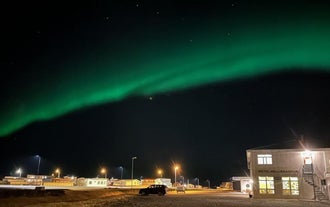 夜空中极光闪耀,Adventure Hotel Hellissandur下方街灯与建筑灯光交相辉映。