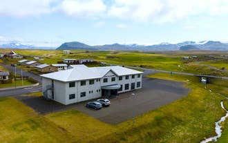 Adventure Hotel Hellissandur sits along a quiet road with mountain views and grassy fields all around.