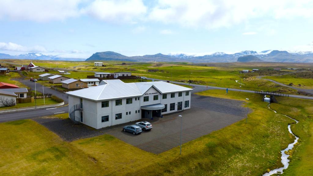Adventure Hotel Hellissandur sits along a quiet road with mountain views and grassy fields all around.