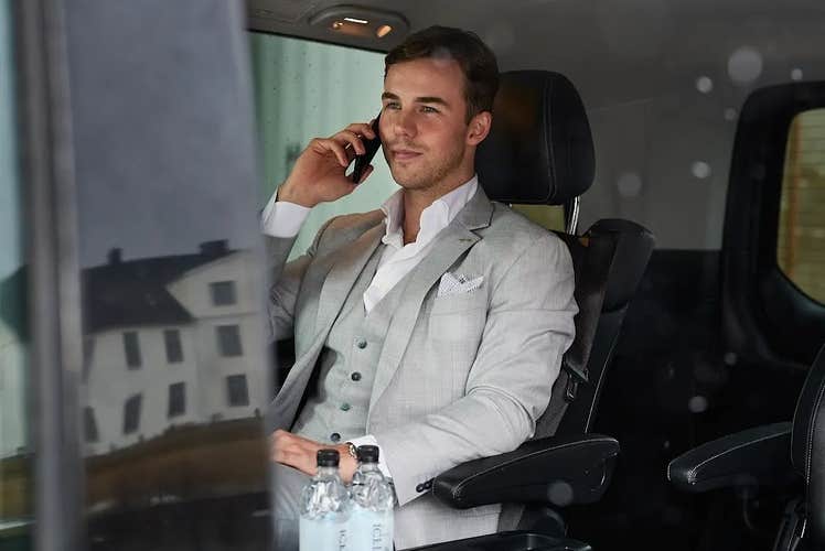 Man in a gray suit on the phone during a private transfer from Keflavik Airport to Reykjavik.