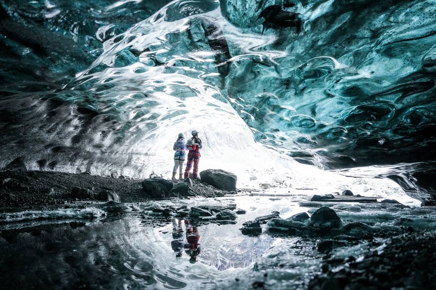 Two travelers photographed inside a blue ice cave in Vatnajokull on an Ice Pic Journeys small-group tour.