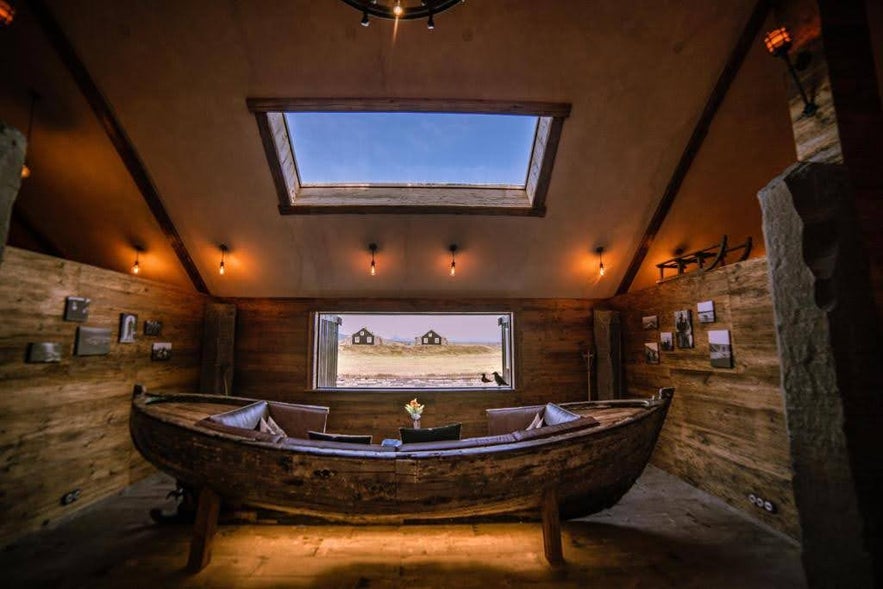 Rustic room at Torfhus Retreat with a boat-shaped sofa and skylight view.