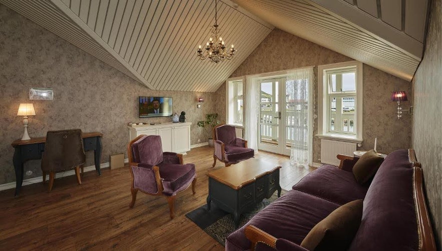 Elegant lounge at Siglo Hotel in Iceland with velvet chairs, a chandelier, and balcony views.