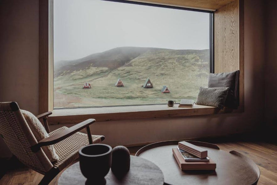 View from Highland Base Kerlingarfjoll in Iceland with A-frame cabins on a misty hillside seen through a large picture window.