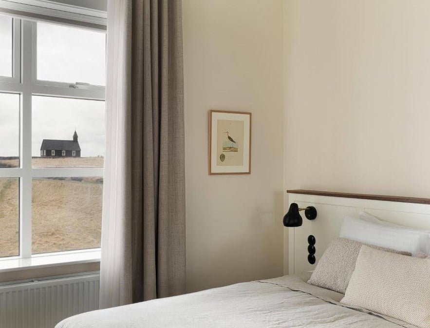 Minimalist bedroom at Hotel Budir in Iceland with a view of the black church through the window.