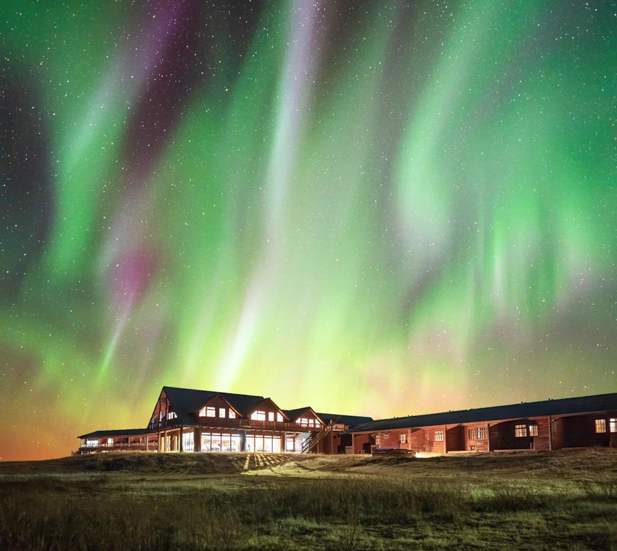 Hotel Ranga in Iceland illuminated under a vivid green and purple northern lights display.