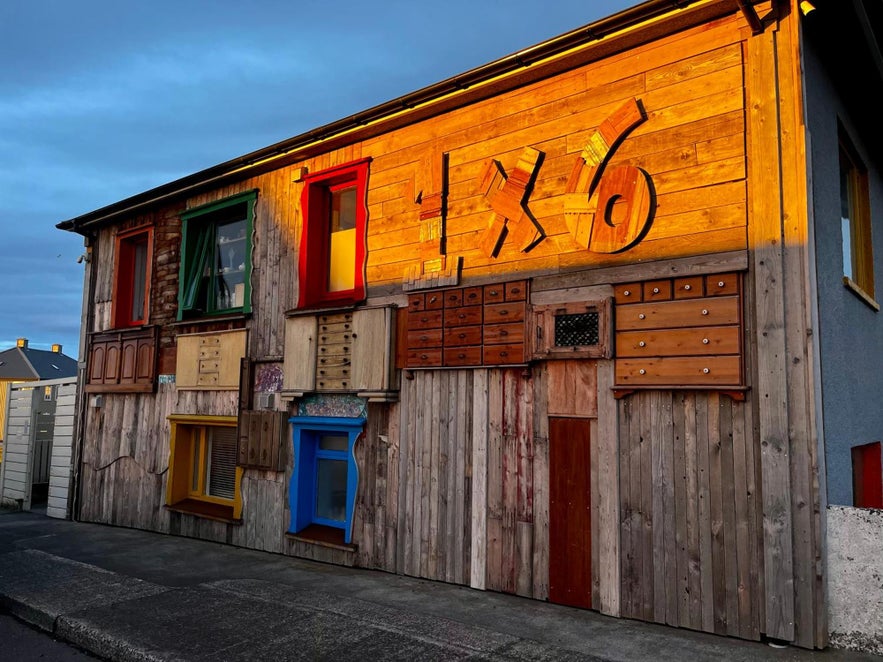 Guesthouse 1x6 in Keflavik with a unique wooden facade decorated with drawers, colorful window frames, and repurposed materials.