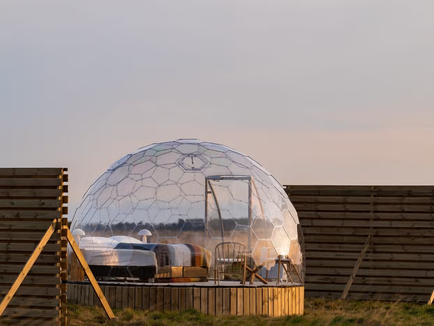 Transparent dome accommodation in Iceland with a cozy bed and minimal furnishings.
