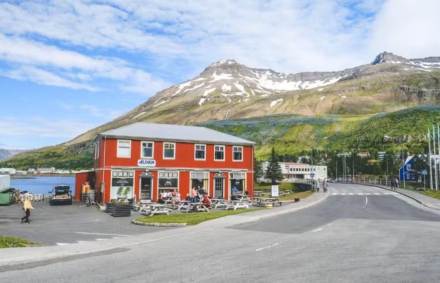 Traditional building of Hotel Aldan in Seydisfjordur, Iceland, with white-trimmed black facade and views of surrounding mountains.