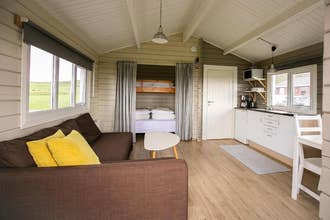 De woonkamer van een cottage bij Moar Cottages, met houten vloeren, een bank, een salontafel, een stapelbed en een keuken.