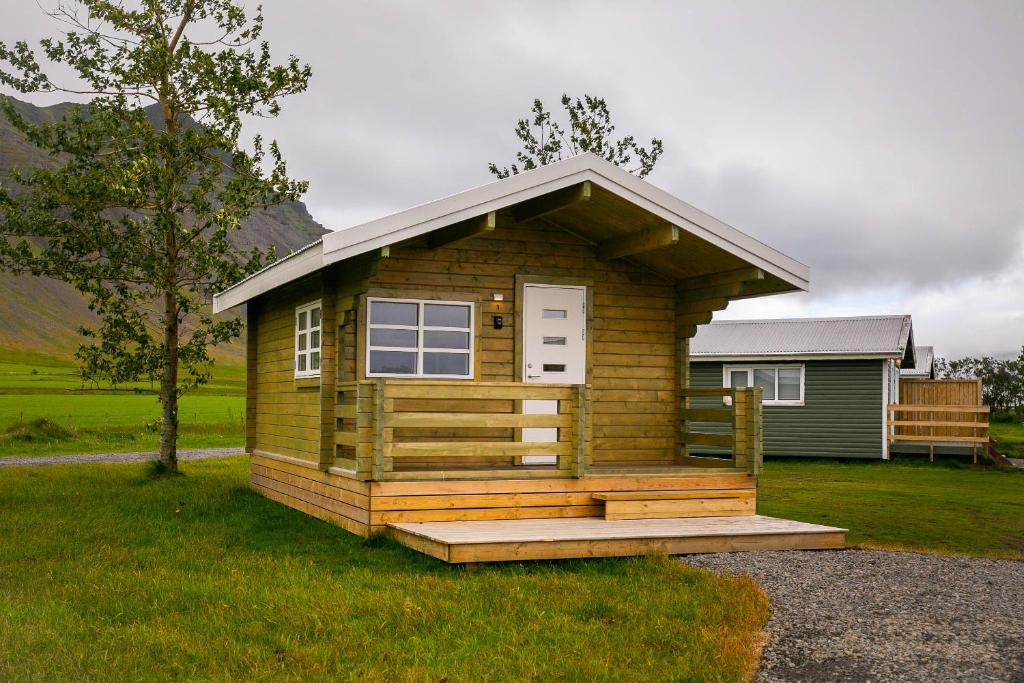 A small rustic cottage with a small terrace outside sits in a grassy field at Moar Cottages in Akranes, West Iceland.