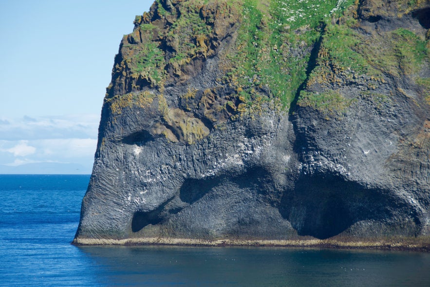 Cliff formation resembling an elephant’s head and trunk dipping into the sea on Heimaey Island, Iceland.