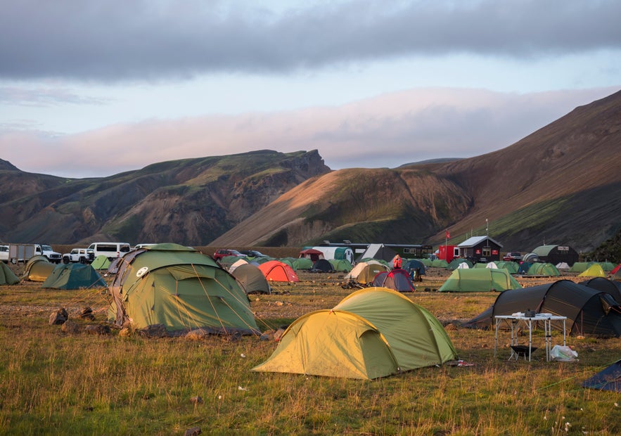 Camping tents in Landmannalaugar with colorful rhyolite mountains in Iceland’s Highlands.