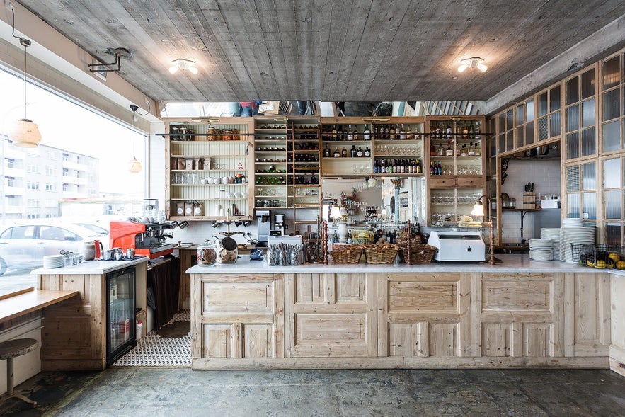 Rustic wooden counter and shelves stocked with glassware and bottles at Kaffihús Vesturbæjar in Reykjavik.