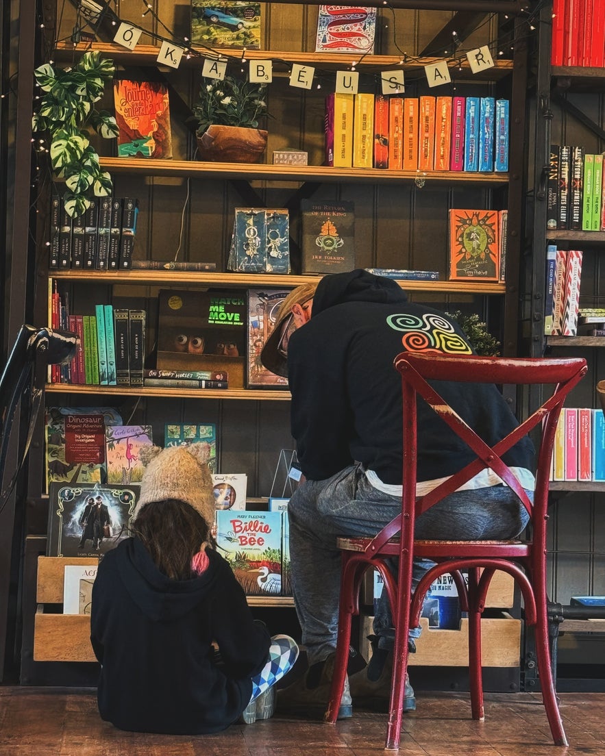A child and adult browsing colorful books at IDA Zimsen Bókakaffi, a cozy Reykjavik book cafe.