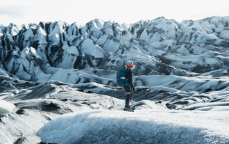 Hiker with helmet standing on ice ridges of Flaajokull Glacier in Iceland.