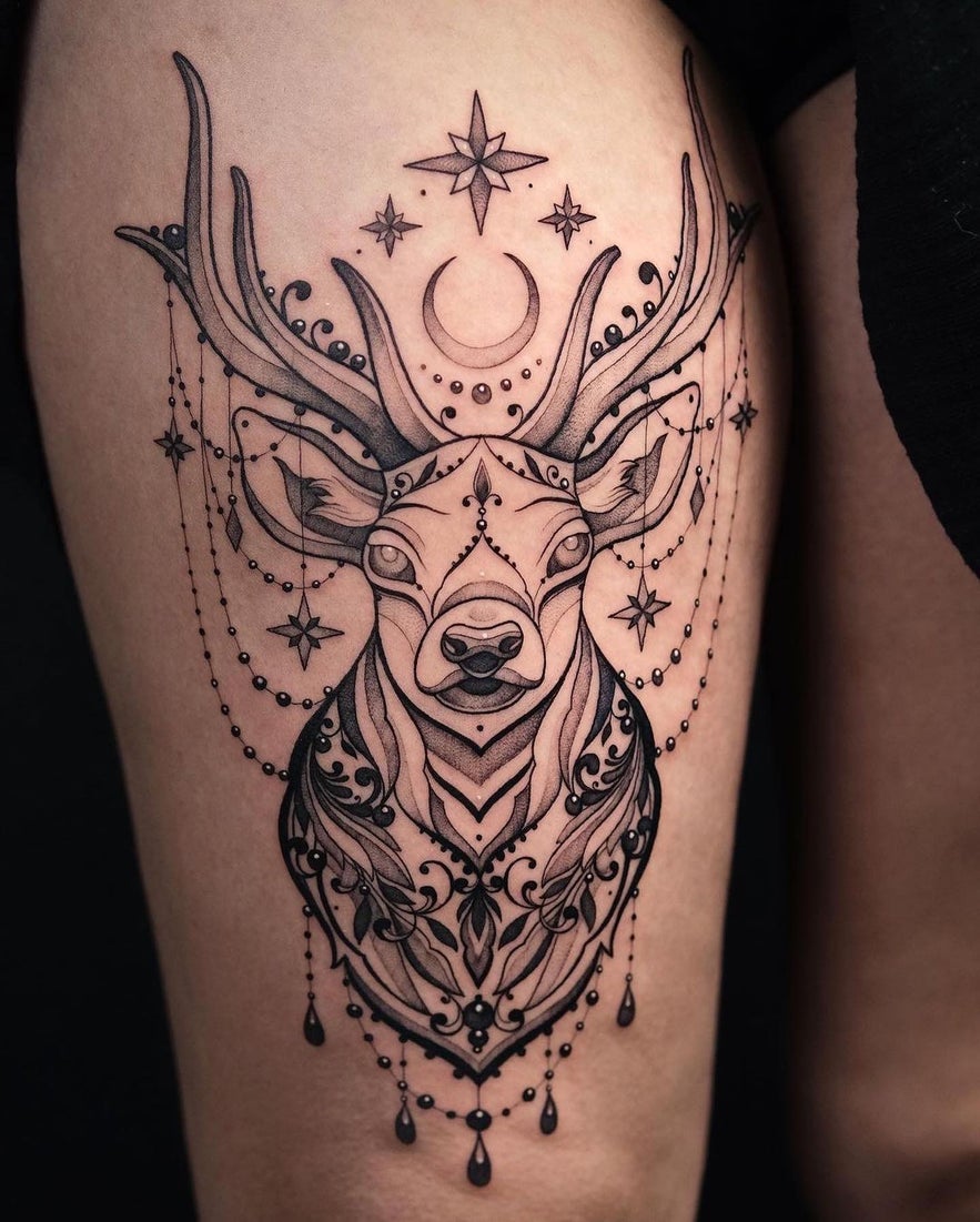 A thigh tattoo featuring a deer with stars and a moon, showcasing a celestial theme.