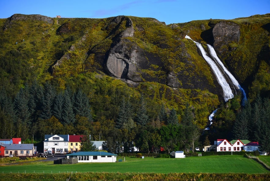Systrafoss Waterfall above Kirkjubaejarklaustur in South Iceland, near Fjadrargljufur Canyon, with village houses and green hills.