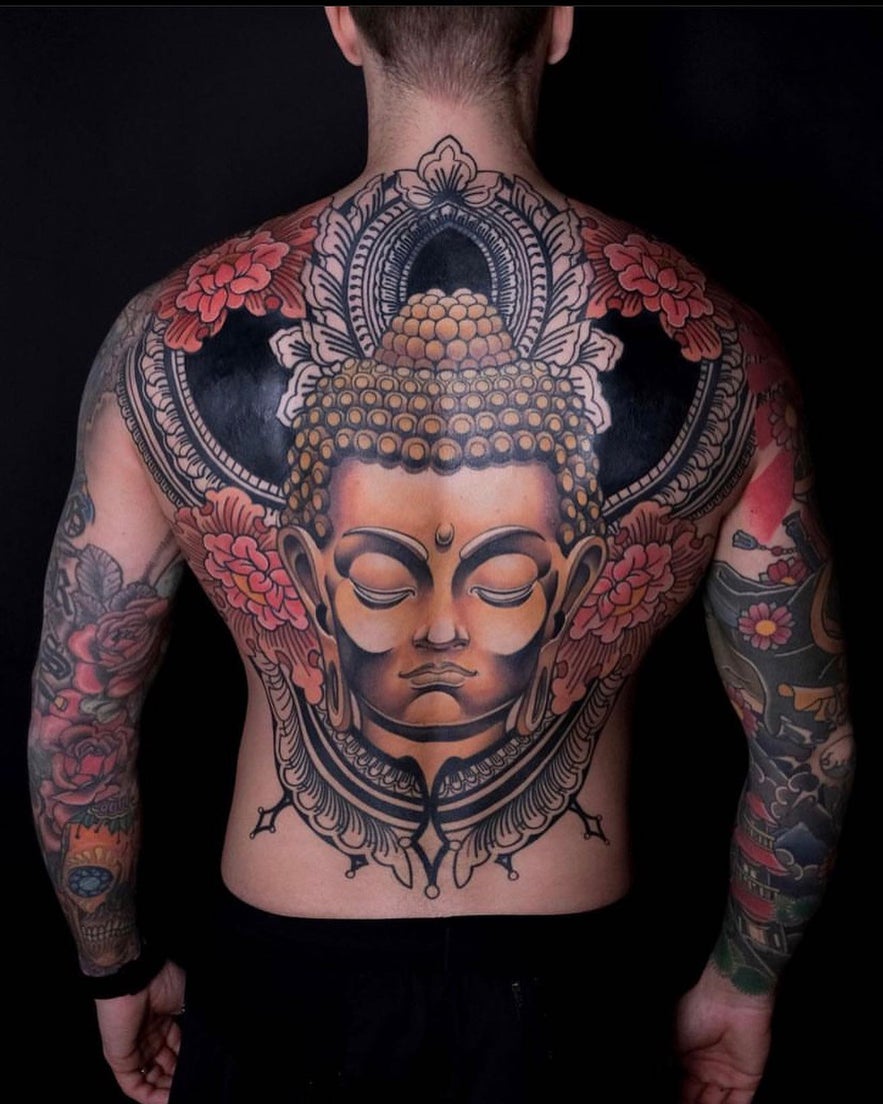 A large Buddha tattoo on the back, featuring ornate details symbolizing tranquility and mindfulness.