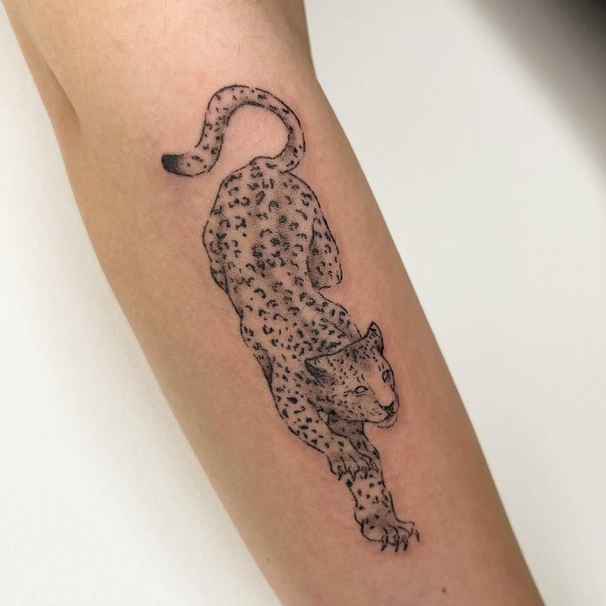 An artistic leopard tattoo on the arm, featuring realistic details and bold lines.