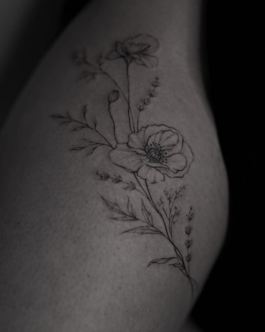 Close-up of a thigh tattoo featuring a detailed flower design.