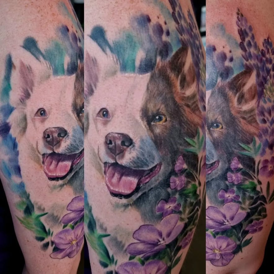 Realistic watercolor-style tattoo of a dog’s face surrounded by purple flowers.