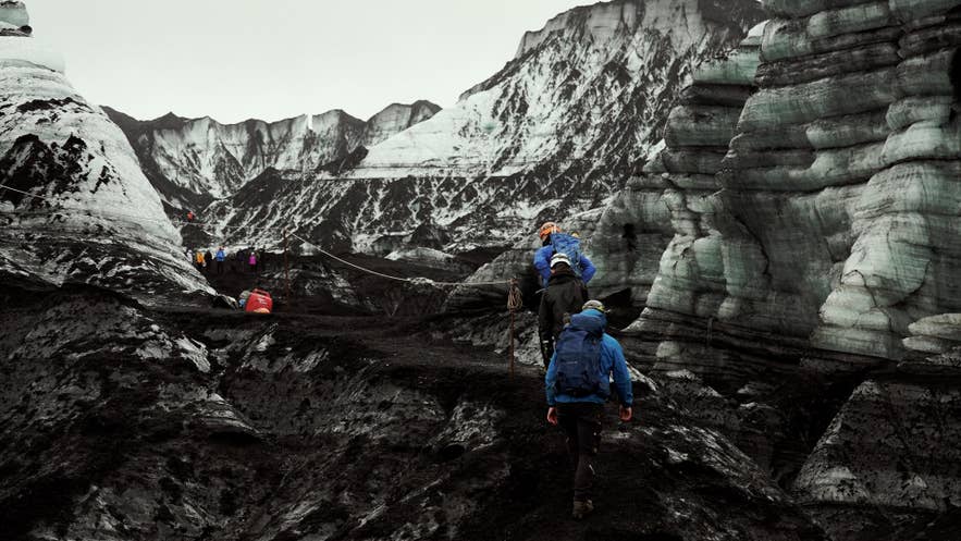 Guided group in helmets climbing an ash-layered glacier slope near Katla Volcano. Guided group in helmets climbing an ash-layered glacier slope near Katla Volcano.