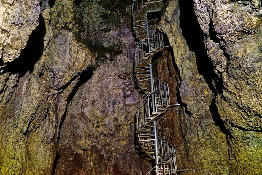 A spiral staircase inside Vatnshellir Cave in Snaefellsnes Peninsula, Iceland, winds through ancient lava rock walls.