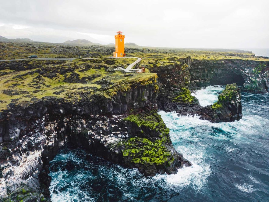 The bright orange lighthouse stands on the rugged Svortuloft Cliffs at the western tip of Iceland’s Snaefellsnes Peninsula, overlooking the wild Atlantic Ocean.