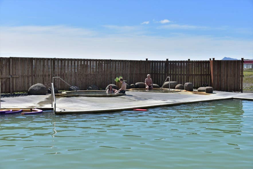 Geothermal outdoor pool at Lýsulaugar Mineral Algae Baths in Iceland with mountain views and clear blue summer skies.