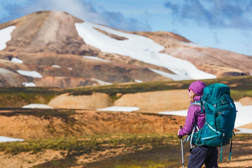 A female hiker with a huge hiking backpack exploring the Laugavegur Trail in Iceland.