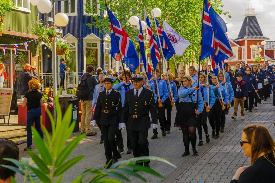 Akureyri hosts a lively parade with people in uniform and Icelandic flags waving high.