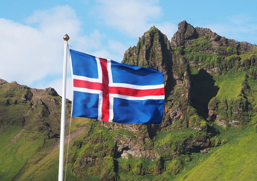 The Icelandic flag waves under the blue sky.
