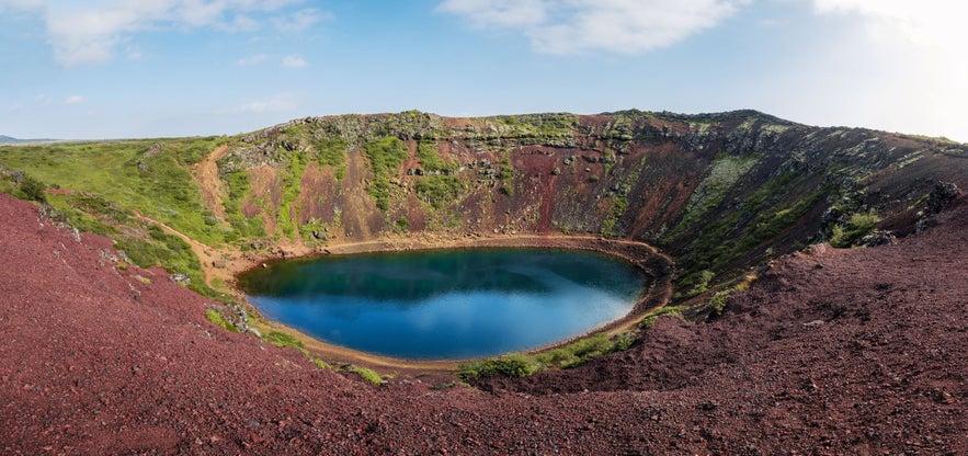 Volcanic red slopes and vivid blue water inside Kerid Crater, a striking geological site on Iceland's Golden Circle.