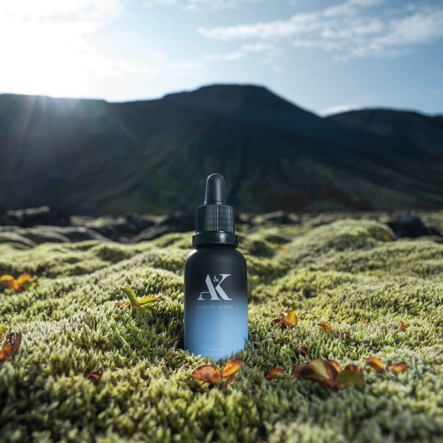 AK Pure Skin Hydrating Ceramide Moisturizer bottle on black sand, surrounded by sparkling ice formations.