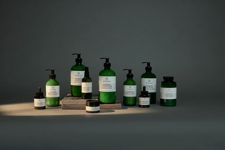 A curated collection of Angan Skincare products in green bottles and jars are neatly displayed. A curated collection of Angan Skincare products in green bottles and jars are neatly displayed.