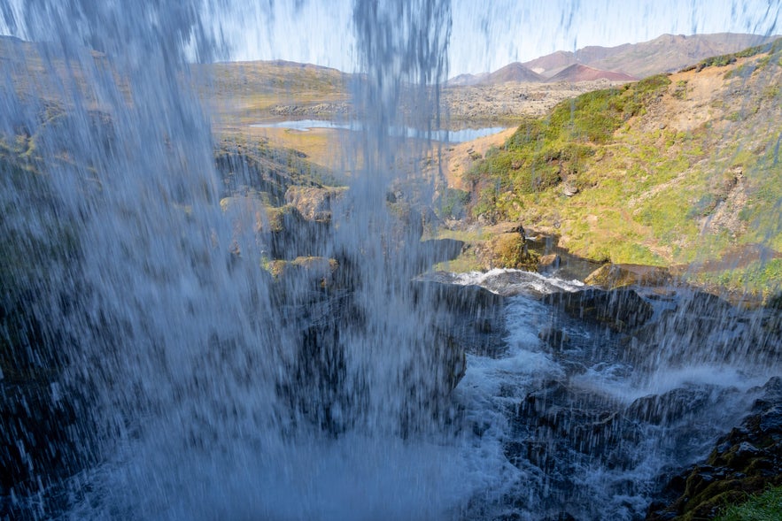 Selvallafoss Waterfall viewed from behind, with a scenic Icelandic landscape.