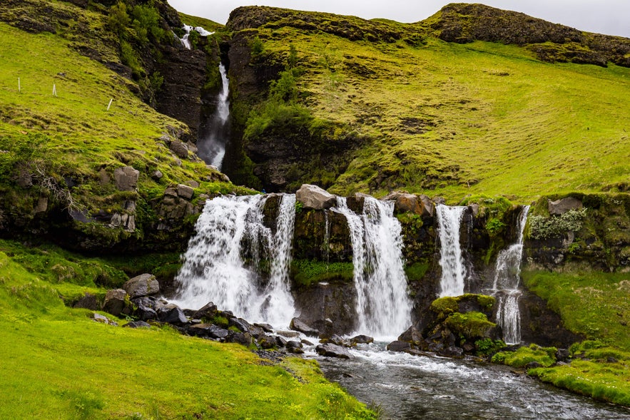 The unique tiered Glugafoss Waterfall cascades down moss-covered hillsides in Iceland and flows into a rocky river.