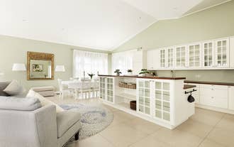 A unique island counter-slash-cabinet is the center of the kitchen with the sink, cupboards, and dining table in the background.