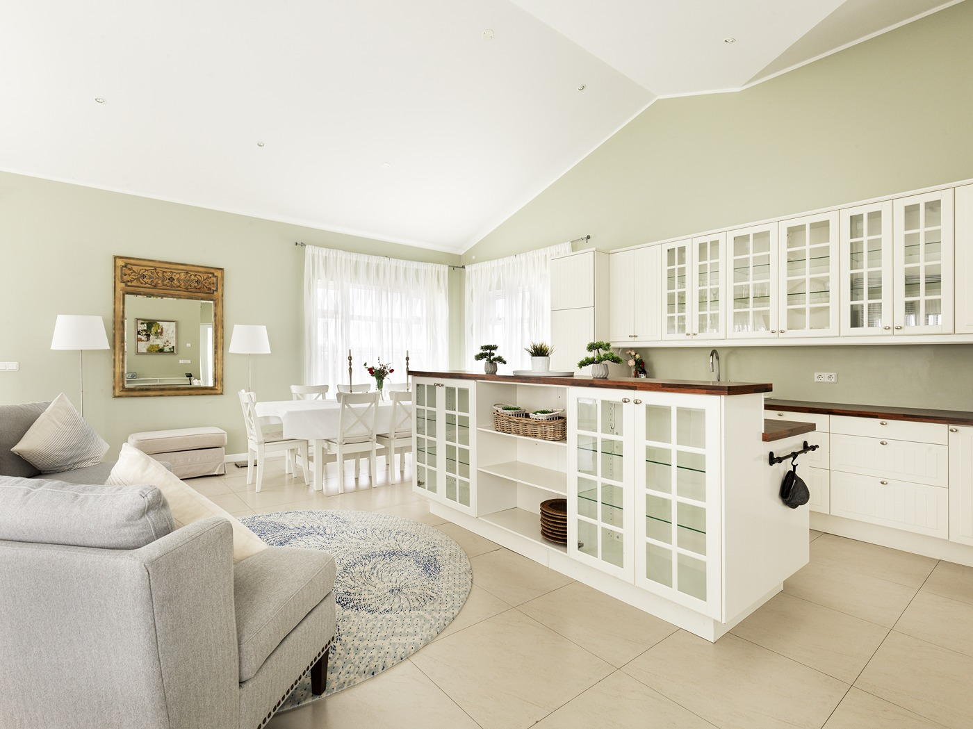 Een uniek keukeneiland met spoelbak en kasten vormt het middelpunt van de keuken, met op de achtergrond de eettafel en kasten.