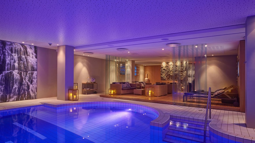 Spa interior at Berjaya, featuring a blue-lit pool, lounge area, and waterfall art.