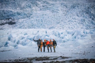 Eine Gruppe von Wanderern in Island posiert fröhlich vor der Kamera, während sich ein riesiger Gletscher im Hintergrund erstreckt.