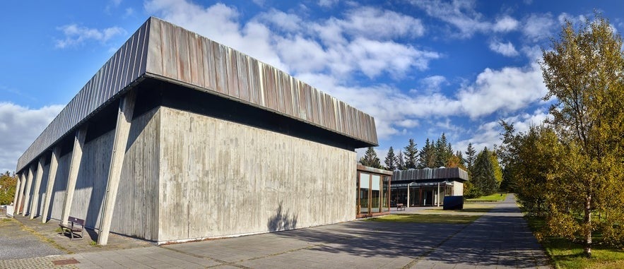 Modernist concrete exterior of Kjarvalssta&eth;ir Art Museum in Reykjav&iacute;k, surrounded by trees under a bright blue sky.