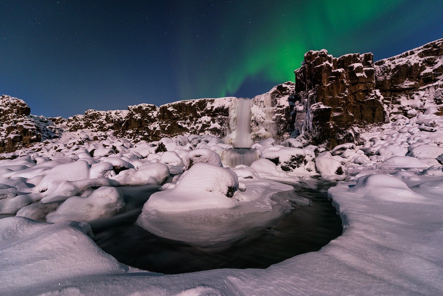 Oxararfoss waterfall in Thingvellir National Park in Iceland, under the northern lights