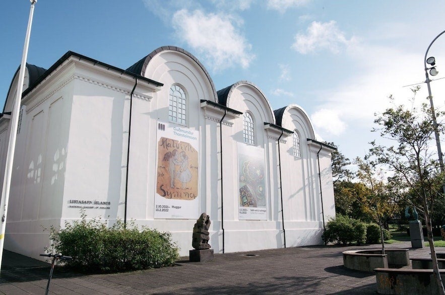 The National Gallery of Iceland in Reykjav&iacute;k, a historic white building with arched windows and contemporary art banners displayed on its fa&ccedil;ade.