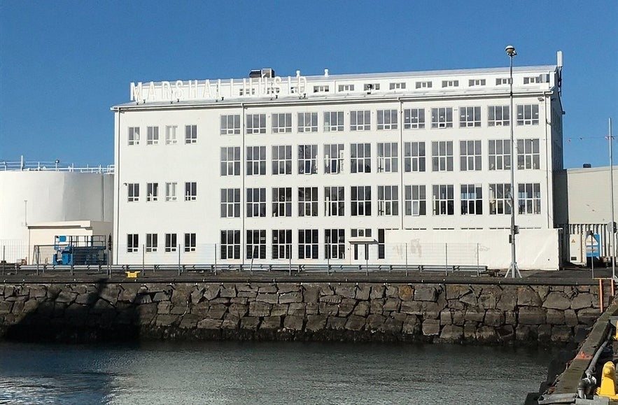 Exterior of the Marshall House in Reykjavík, home to the Living Art Museum, with large industrial-style windows facing the harbor.