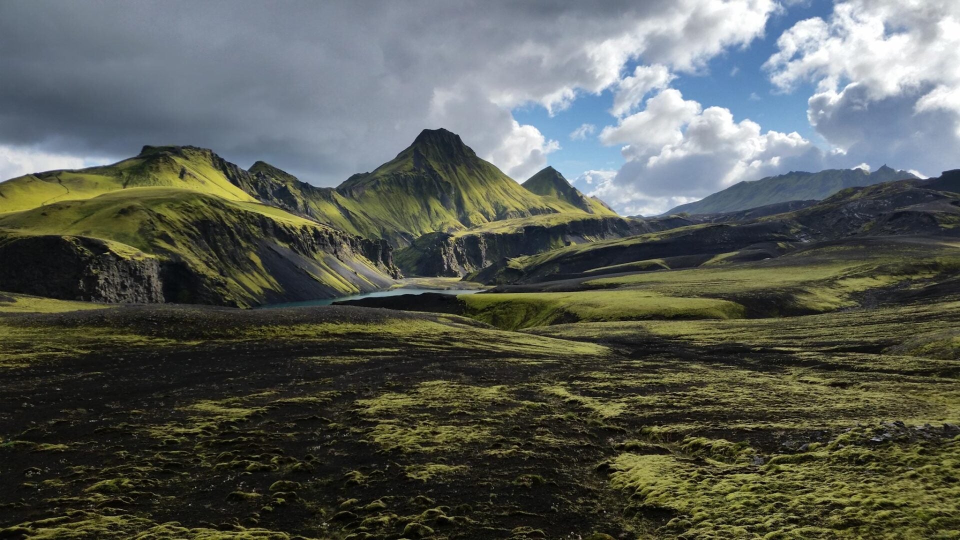 A scenic view of South Iceland's Highlands, with grass-covered mountains in the distance.