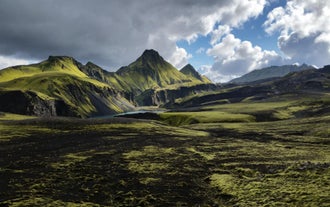 A scenic view of South Iceland's Highlands, with grass-covered mountains in the distance.