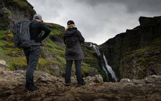 Bezoekers staan aan de rand van de Glymur-kloof om de waterval te bewonderen.
